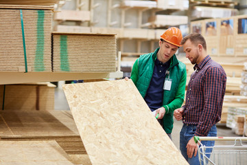 expert in his field, warehouse worker consult customer, show wooden board and talk about all...