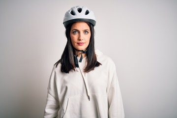 Young cyclist woman with blue eyes wearing bike helmet over isolated white background with serious expression on face. Simple and natural looking at the camera.