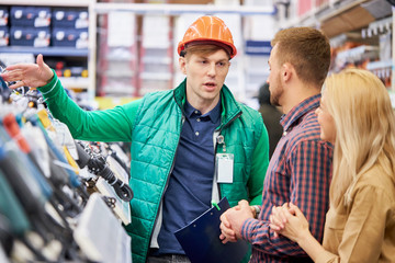 affable caucasian male warehouse worker consult and help to customers, show the best variant of...