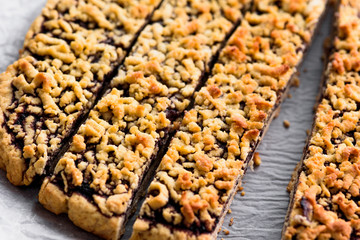 Grated pie with jam on parchment paper top view, cut along