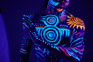 young african man blur with ultraviolet body art, fluorescent prints glows on neon light, isolated in studio. mystery, luminescence, fluorescence, ethnic body art