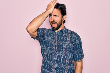Young handsome hispanic bohemian man wearing hippie style over pink background surprised with hand...