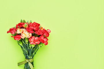 Carnation flowers bouquet on green background. Mother's day, Valentines Day, Birthday celebration concept. Copy space, top view