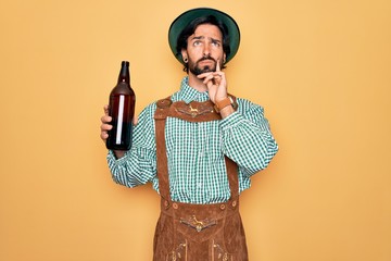 Young handsome man wearing tratidional german octoberfest custome and drinking beer from bottle...