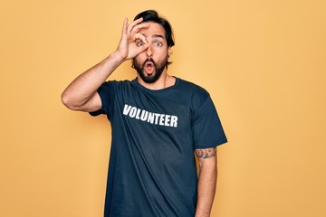 Young handsome hispanic volunteer man wearing volunteering t-shirt as social care doing ok gesture...