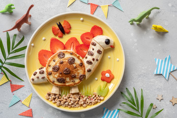 Cute dinosaur shaped pancake with fruits for kids breakfast