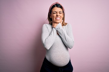 Young beautiful brunette woman pregnant expecting baby over isolated pink background shouting and...