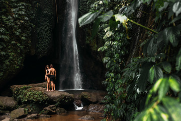 Lovers at the waterfall. Couple admiring a beautiful waterfall in Indonesia. Couple on vacation in Bali. Honeymoon trip. The couple is traveling in Asia. Vacation on the island of Bali