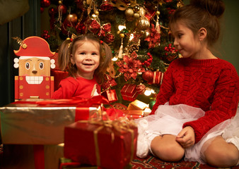 Little sisters unpack gifts smile laugh Cozy atmosphere of Christmas New Year Christmas tree...