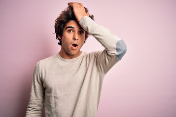 Young handsome man wearing casual t-shirt standing over isolated pink background surprised with hand on head for mistake, remember error. Forgot, bad memory concept.