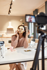 Discover a new product. Young female blogger recording a tutorial video for her beauty blog about skincare routine. Vlogger testing face mask, recording video for social network