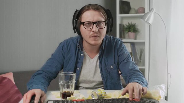 Young man playing video game at home feeling Upset after losing and showing indecent gesture