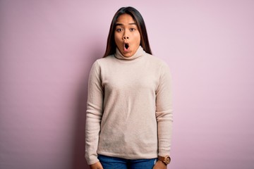 Young beautiful asian girl wearing casual turtleneck sweater over isolated pink background afraid and shocked with surprise expression, fear and excited face.