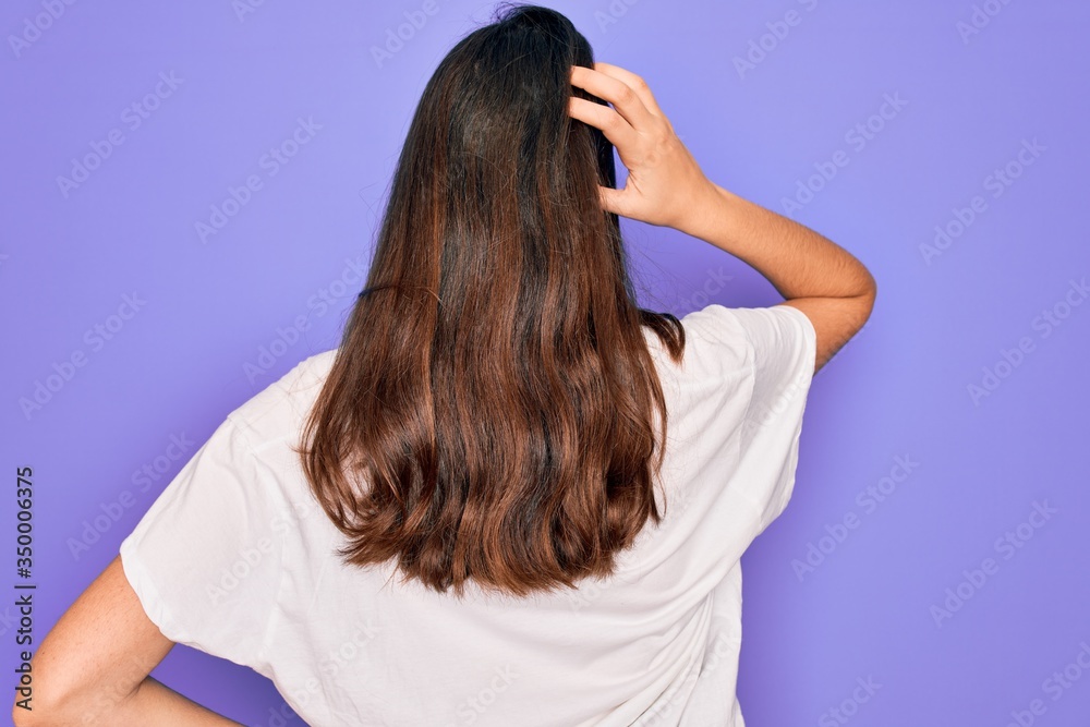 Poster Young beautiful brunette woman wearing casual white t-shirt over purple background Backwards thinking about doubt with hand on head