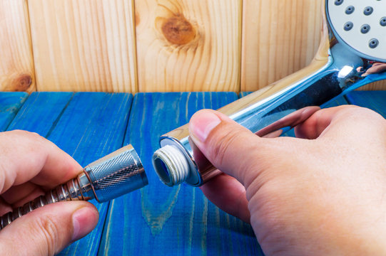 Mester plumber on a desktop connects a hose to a shower head