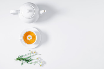 White chamomiles and teapot on white background. Herbal tea of chamomile flower. Chamomile tea concept. Flat lay, top view, copy space