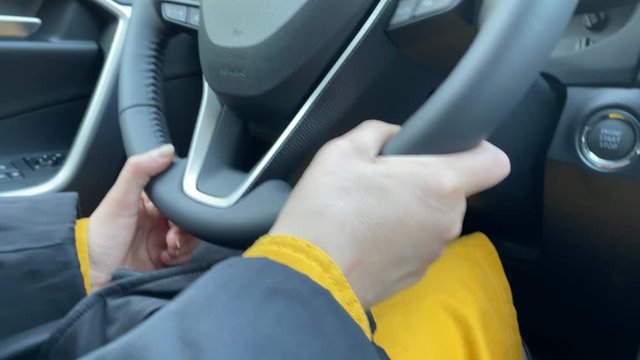 Woman driver driving her crossover suv car, female hands on the steering wheel close-up.