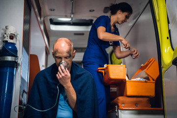 A medical worker preparing a dropping tube, a man rescued from an accident in the foreground