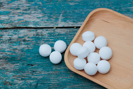 Moth balls on the wooden plate over wooden table