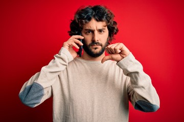 Handsome man with beard having conversation talking on the smartphone over red background with...