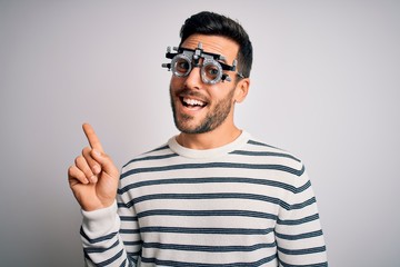 Naklejka premium Young handsome man with beard wearing optometry glasses over isolated white background with a big smile on face, pointing with hand and finger to the side looking at the camera.