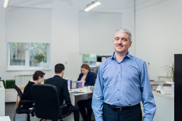 Fototapeta premium Senior businessman in his office with people having a meeting in