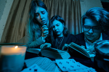 Two women and a guy are reading a mysterious books, close view