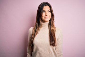 Fototapeta premium Young beautiful girl wearing casual turtleneck sweater standing over isolated pink background smiling looking to the side and staring away thinking.