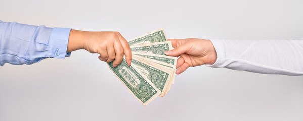 Two hands of caucasian young women doing transaction. Woman giving bunch of dollars banknote to other person over isolated white background