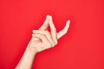 Hand of caucasian young man showing fingers over isolated red background snapping fingers for...