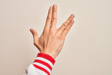 Hand of caucasian young man showing fingers over isolated white background greeting doing Vulcan...