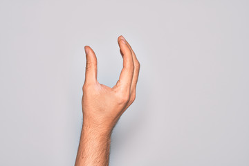 Hand of caucasian young man showing fingers over isolated white background picking and taking invisible thing, holding object with fingers showing space