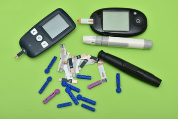 2  glucometer, lancet, spare needles on green background 