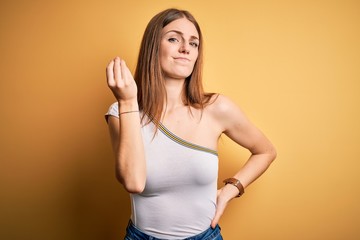 Young beautiful redhead woman wearing casual t-shirt over isolated yellow background Doing Italian gesture with hand and fingers confident expression