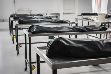 Covered human corpses on tables in a morgue / mortuary waiting for identification, autopsy, burial or cremation. Taken in Armenia, Colombia.