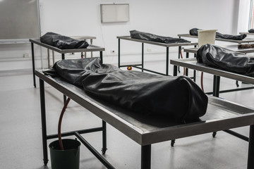 Covered human corpses on tables in a morgue / mortuary waiting for identification, autopsy, burial or cremation. Taken in Armenia, Colombia.