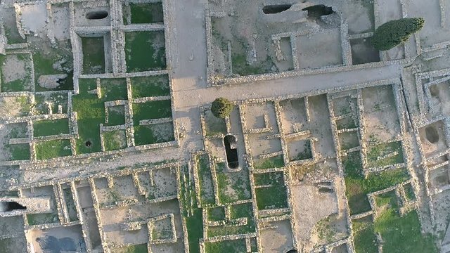 AERIAL DRONE TOP DOWN OF MEDITERRANEAN ROMAN RUINES WITH ROCKS AND CYPRESS