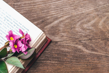 Open book with a bouquet of pink flowers on a old wooden background.Copy space for text