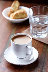 Cup of coffee with cantuccini (Italian cookies) on rustic wooden background.