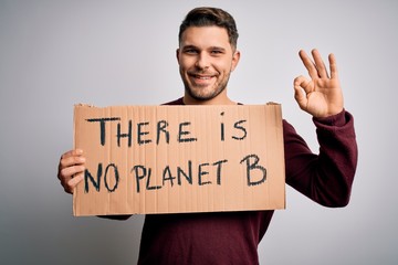 Young activist man holding protest banner for climate change and environment change doing ok sign with fingers, excellent symbol