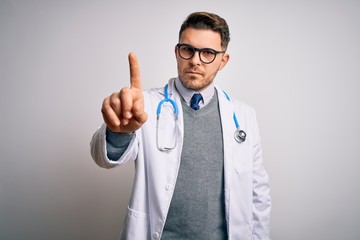 Young doctor man with blue eyes wearing medical coat and stethoscope over isolated background Pointing with finger up and angry expression, showing no gesture