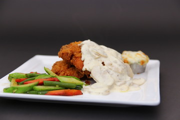 Fried Chicken Breasts with White Cheese Sauce and Mash Potato served on a White Ceramic Dish