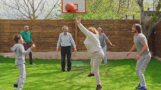 Family playing with a basketball in the back yard.