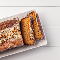 Banana loaf cake with nuts on top cut open wooden table top view.