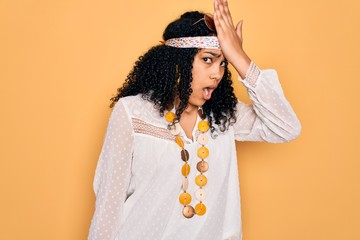 Young african american curly hippie woman wearing sunglasses and vintage accessories surprised with...