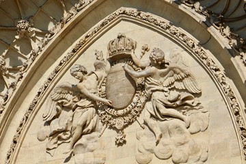 Fototapeta na wymiar Pediment of Sainte Croix Cathedral in Orléans City (France) shot slightly from underneath during daytime with a gothic arch depicting two angels surrounding a coat of arms headed by a crown