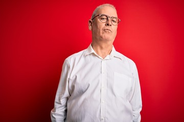 Obraz premium Middle age handsome hoary man wearing casual shirt and glasses over red background Relaxed with serious expression on face. Simple and natural looking at the camera.