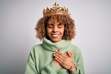Young african american woman wearing golden crown of queen over isolated white background smiling...