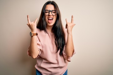 Young brunette elegant woman wearing glasses over isolated background shouting with crazy...