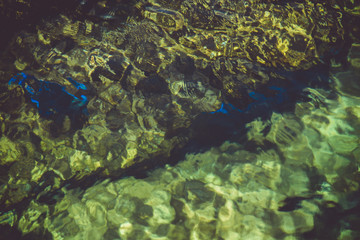 beautiful lagoon with clear water, moss rocks and green foliage in the background 